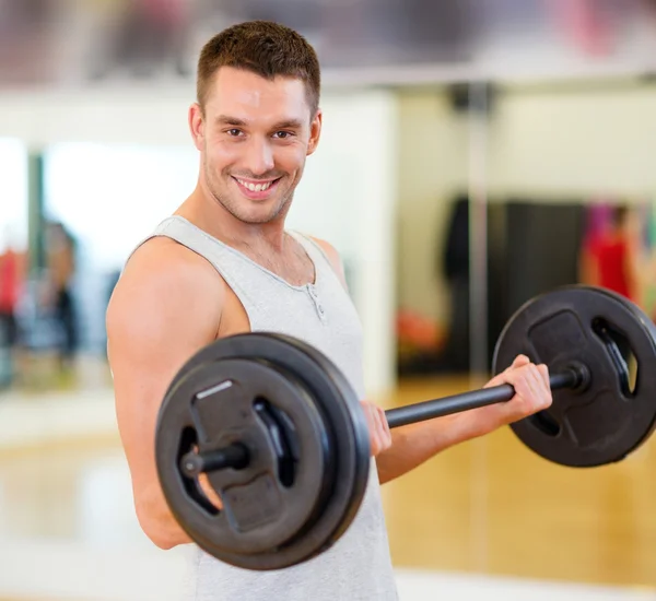 Uomo sorridente con bilanciere in palestra — Foto Stock