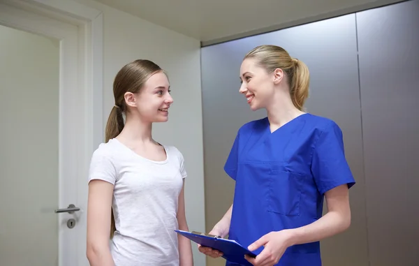 Smiling nurse with clipboard and girl at hospital — Stock Photo, Image