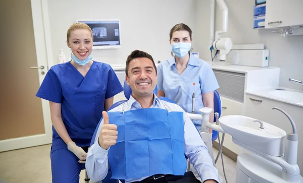 Dentistas mujeres felices con el hombre paciente en la clínica —  Fotos de Stock