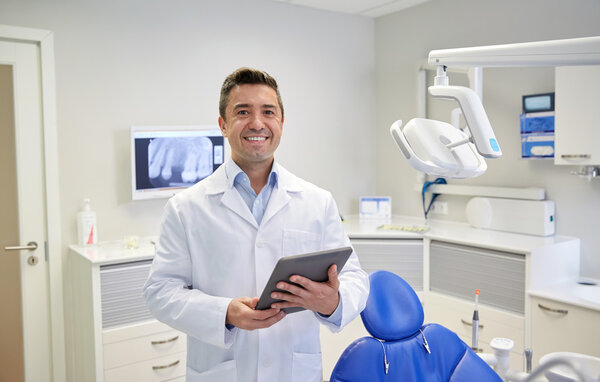 Happy male dentist with tablet pc at dental clinic — Zdjęcie stockowe