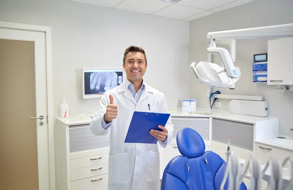 Feliz dentista masculino mostrando pulgares hacia arriba en la clínica —  Fotos de Stock