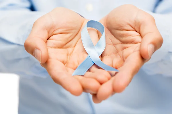 Hands with blue prostate cancer awareness ribbon — Stock Photo, Image