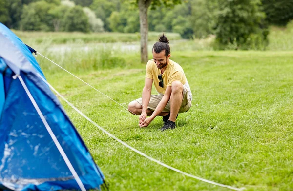 Homem feliz a montar tenda ao ar livre — Fotografia de Stock