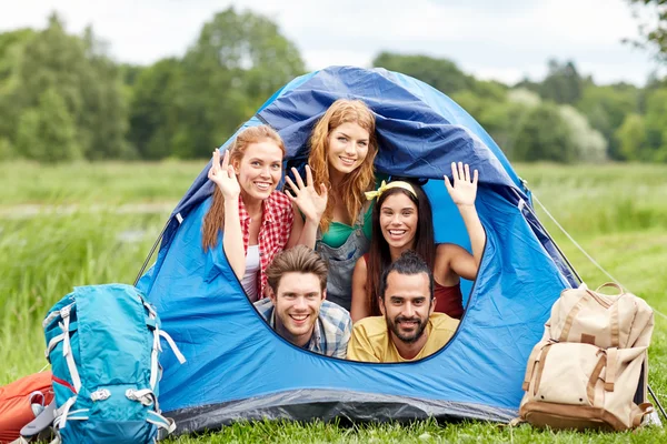 Amigos felices con mochilas en tienda de campaña en el camping —  Fotos de Stock