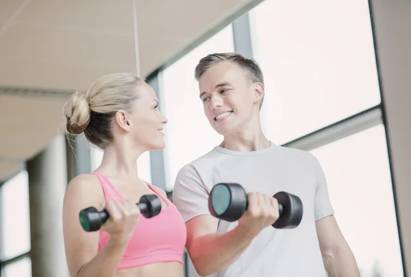 Spor salonunda kişisel antrenörüyle gülümseyen genç bir kadın. — Stok fotoğraf