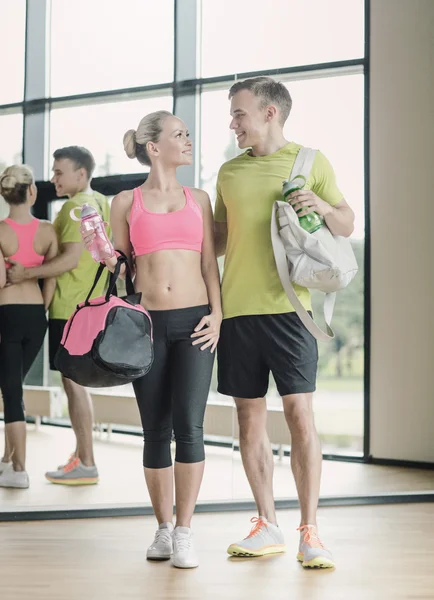 Coppia sorridente con borracce in palestra — Foto Stock