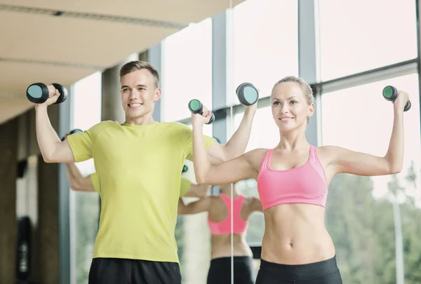 Uomo e donna sorridente con manubri in palestra — Foto Stock