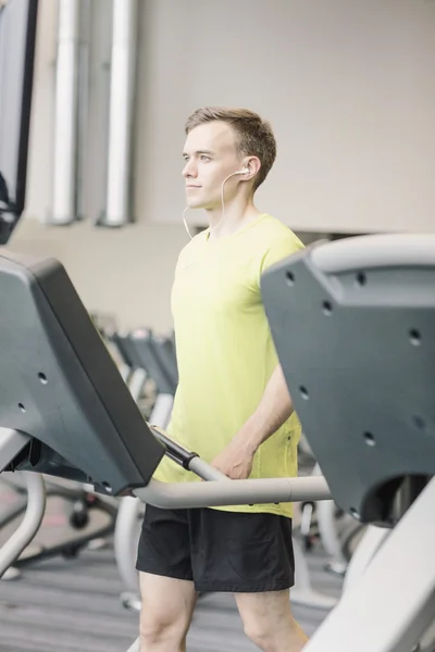 Homme avec smartphone faisant de l'exercice sur tapis roulant en salle de gym — Photo