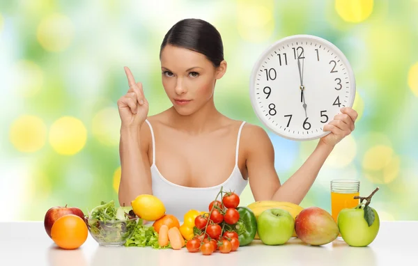 Woman with healthy food and clock warning — Stockfoto