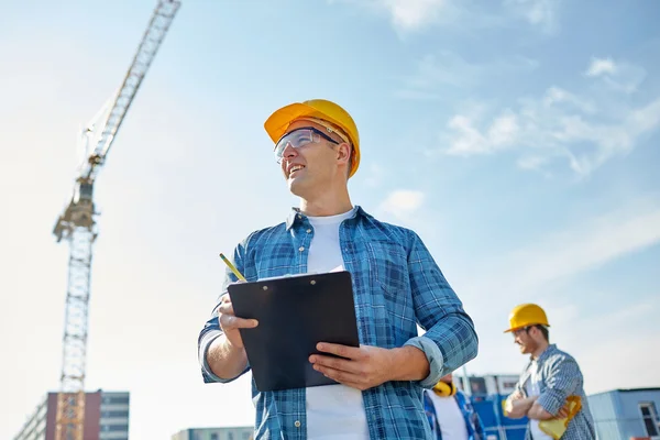 Builder i hardhat med Urklipp på konstruktion — Stockfoto