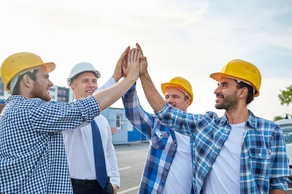 Close up van bouwers in hardhats maken van hoge vijf — Stockfoto