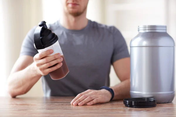 Close up of man with protein shake bottle and jar — Stock Photo, Image