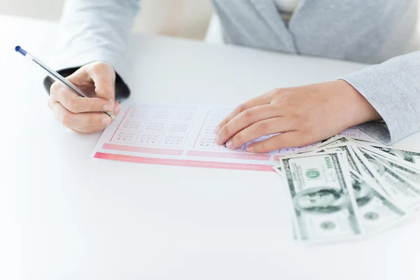 Primo piano delle mani con biglietto della lotteria e denaro — Foto Stock