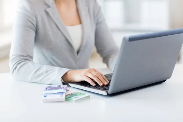 Närbild av kvinna händer med laptop och pengar — Stockfoto