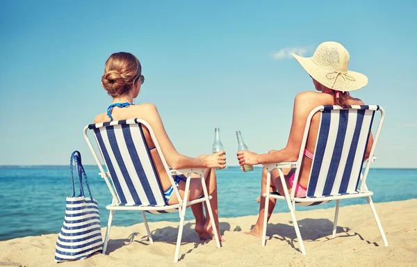 Mulheres felizes banhos de sol em lounges na praia — Fotografia de Stock