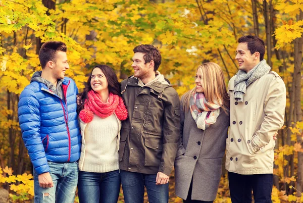 Group of smiling men and women in autumn park — Stock Photo, Image