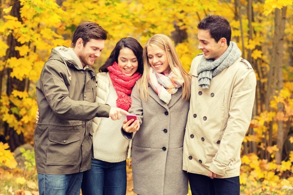 Amigos sonrientes con teléfonos inteligentes en el parque de la ciudad — Foto de Stock