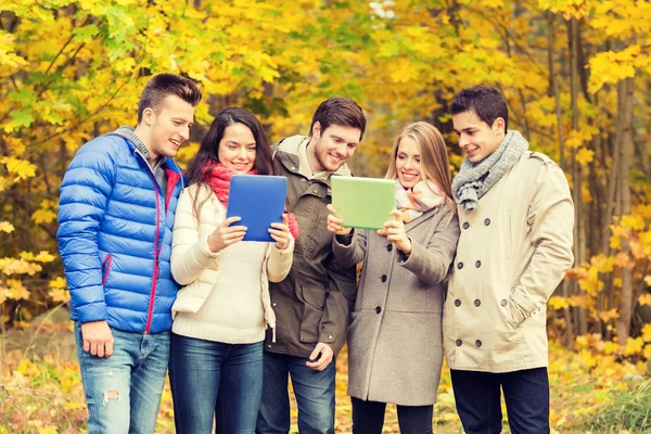 Gruppo di amici sorridenti con tavolette in parco — Foto Stock