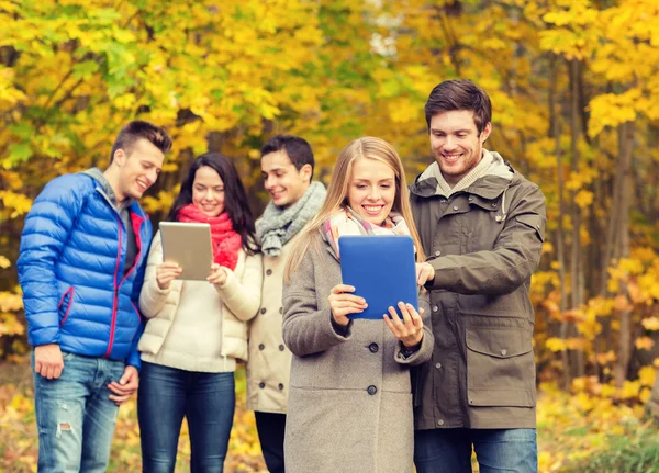 Gruppo di amici sorridenti con tavolette in parco — Foto Stock