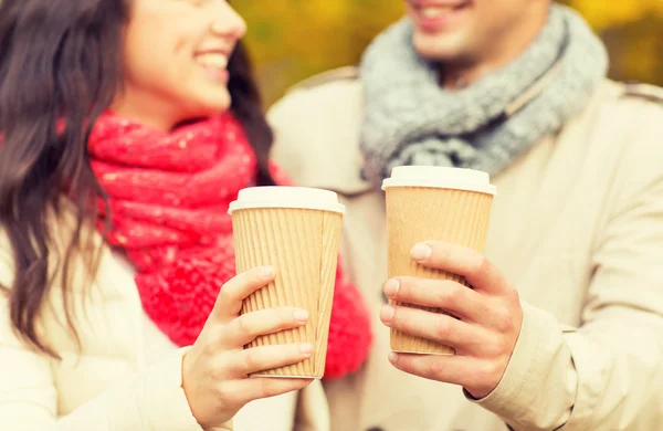 Casal sorrindo com xícaras de café no parque de outono — Fotografia de Stock