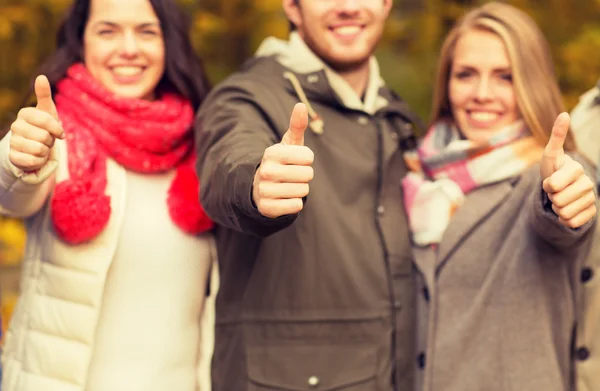 Amigos felices mostrando pulgares hacia arriba en el parque de otoño —  Fotos de Stock