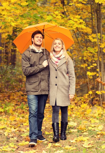 Smiling couple with umbrella in autumn park — Stock Photo, Image