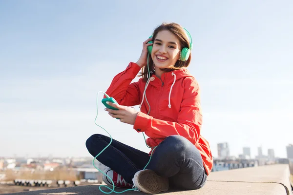 Gelukkig jonge vrouw met smartphone en hoofdtelefoons — Stockfoto