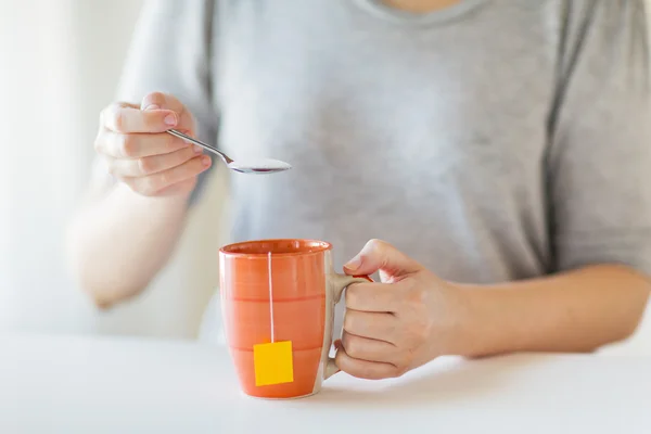 Primer plano de la mujer que añade azúcar a la taza de té — Foto de Stock