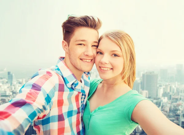 都市の背景にスマート フォンで笑顔のカップル — ストック写真