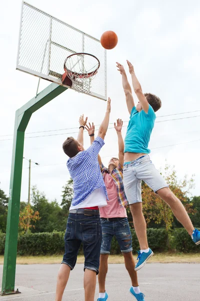 Groep van gelukkig jeugdvrienden spelen basketbal — Stockfoto