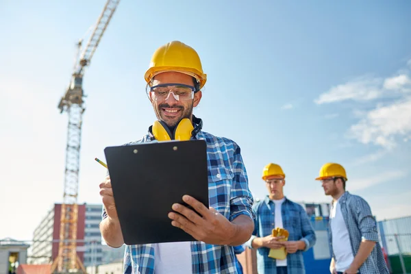 Builder i hardhat med Urklipp på konstruktion — Stockfoto