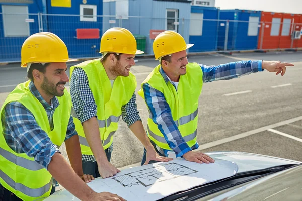 Close up of builders with blueprint on car hood — Stock Photo, Image