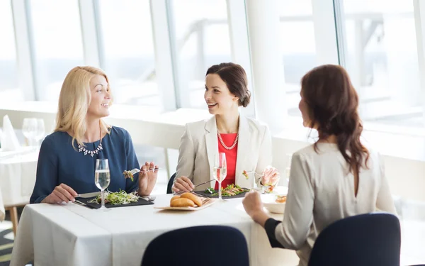 Onnelliset naiset syövät ja puhuvat ravintolassa — kuvapankkivalokuva