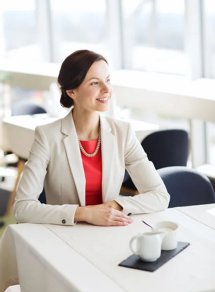 Mujer feliz sentada en la mesa en el restaurante — Foto de Stock