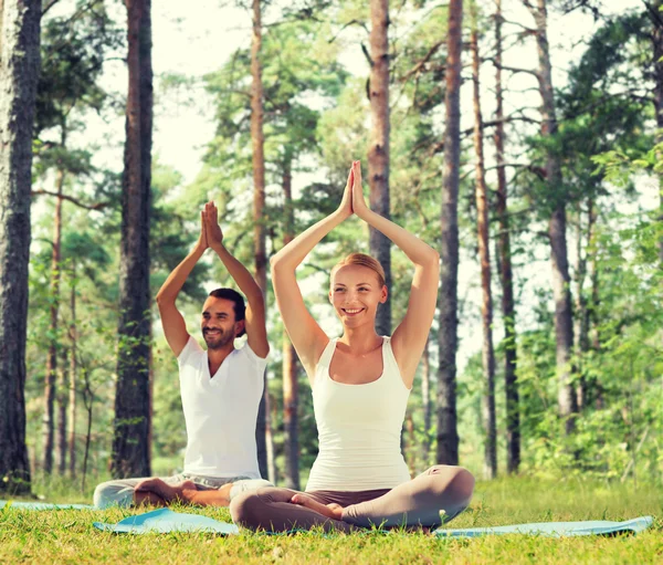 Cuplu zâmbind făcând exerciții de yoga în aer liber — Fotografie, imagine de stoc