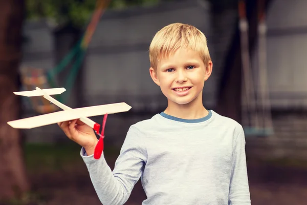 Smiling little boy holding a wooden airplane model — Stock Photo, Image