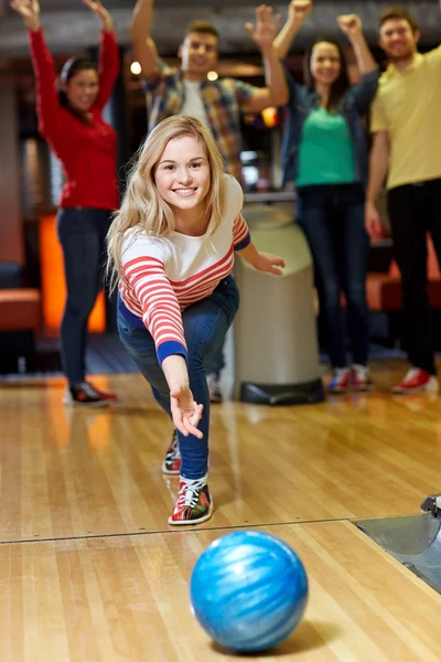Happy young woman throwing ball in bowling club — Stock Photo, Image