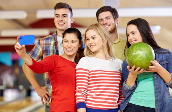 Gelukkige vrienden met smartphone in bowlingclub — Stockfoto