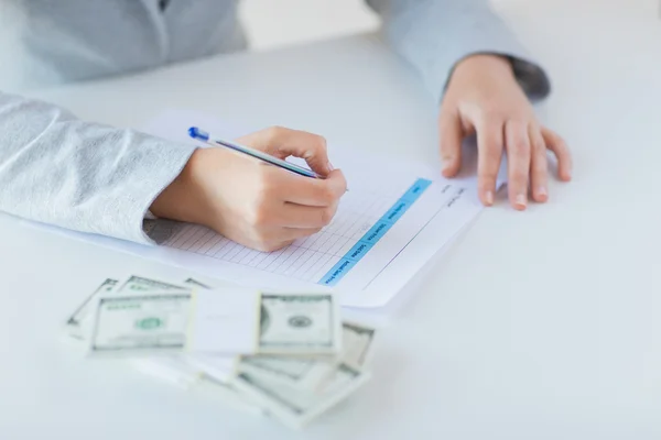 Nahaufnahme der Hände mit Geld, das Steuerformular ausfüllt — Stockfoto