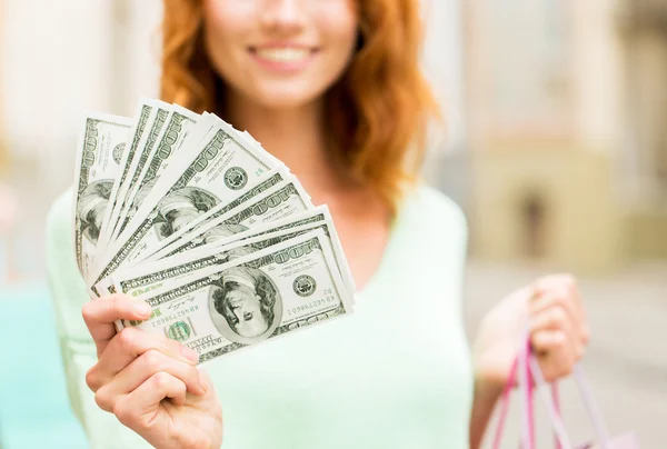 Close up of woman with shopping bags and money — Stock Photo, Image