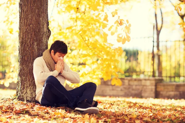 Zieke man met weefsel van het papier in de herfst park — Stockfoto