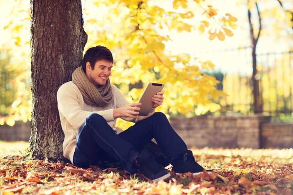 Sonriente joven con la tableta de la PC en el parque de otoño —  Fotos de Stock