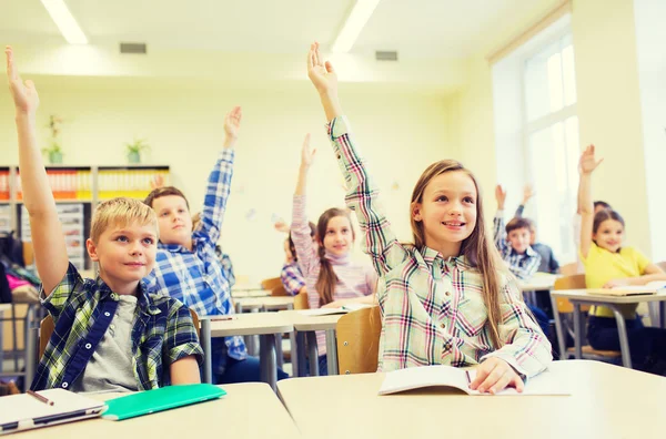 Groep van school kinderen verhogen handen in klas — Stockfoto