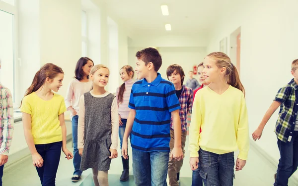 Gruppe af smilende skolebørn gå i korridor - Stock-foto