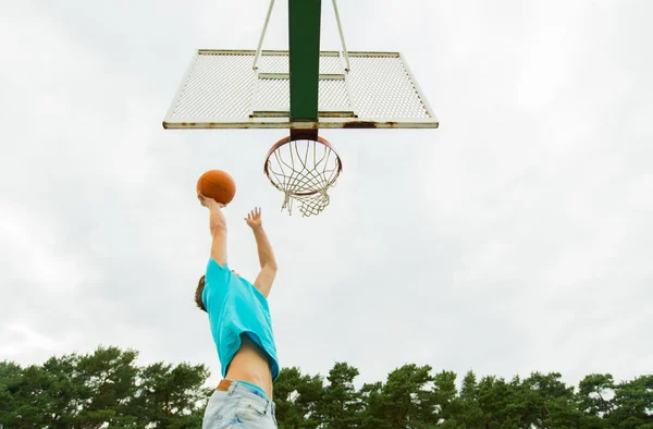 Mladý muž hraje basketbal venku — Stock fotografie