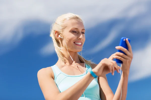 Gelukkige vrouw met smartphone en oortelefoons outdoors — Stockfoto