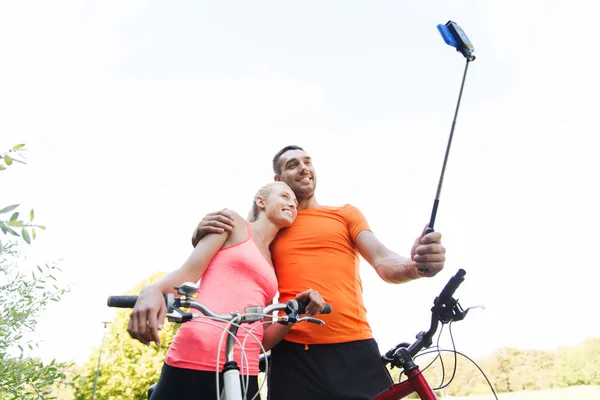 Par med cykel och smartphone selfie stick — Stockfoto