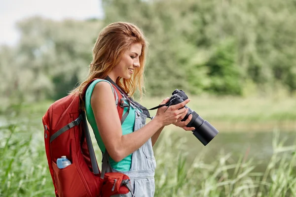 Mulher feliz com mochila e câmera ao ar livre — Fotografia de Stock