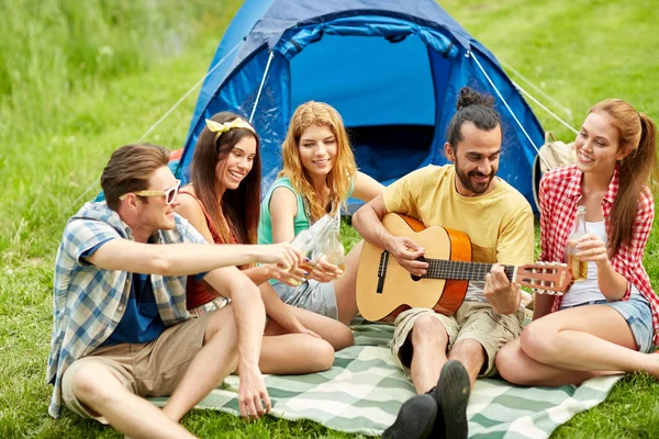 Happy friends with drinks and guitar at camping — Stock Photo, Image