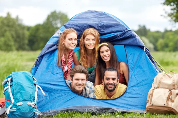 Happy friends with backpacks in tent at camping — Stock Photo, Image